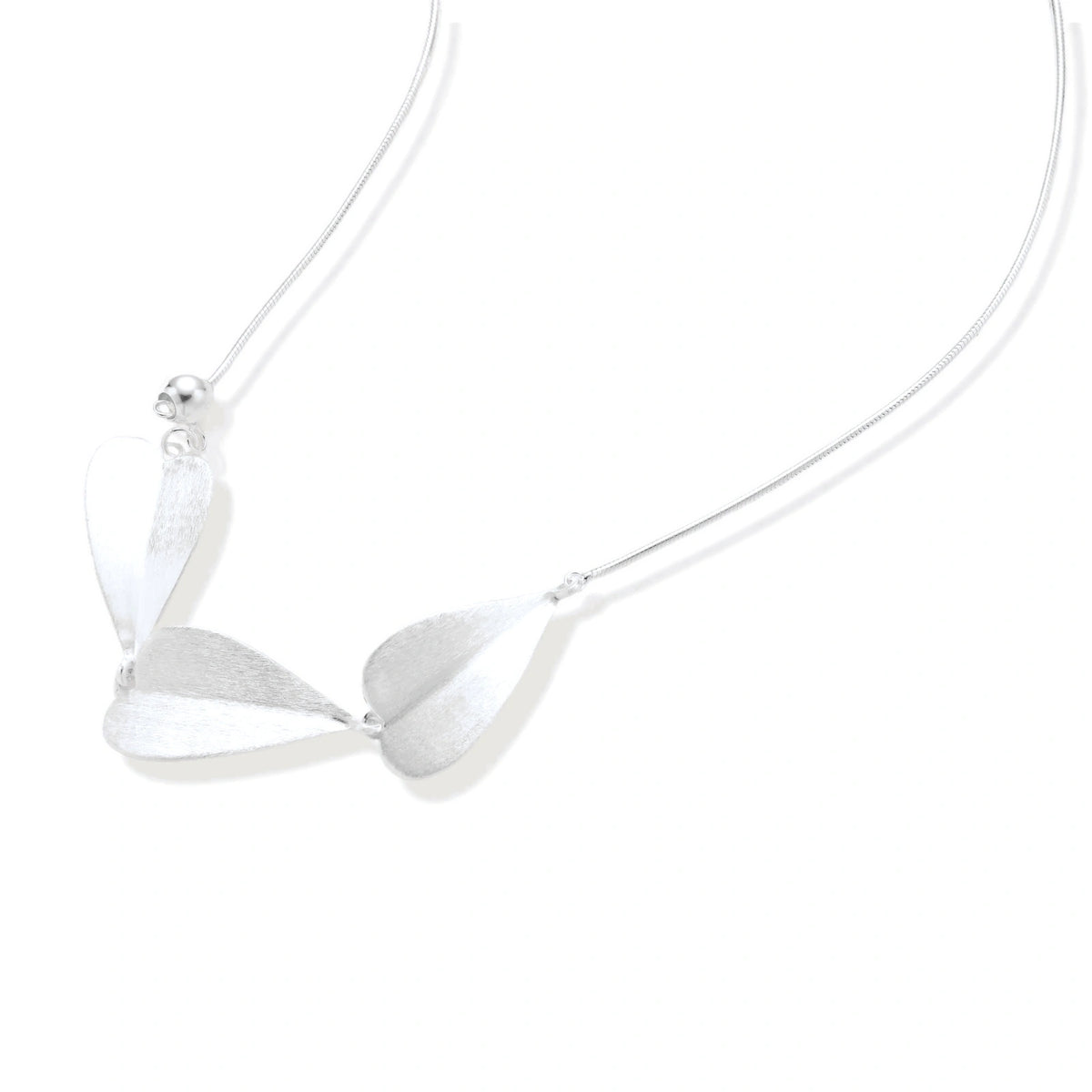 Minimalist sterling silver necklace with three brushed leaf-shaped pendants on delicate chain against white background