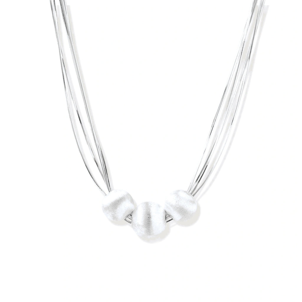 Sterling silver multi-strand necklace with three brushed round beads on cream background