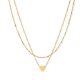 Delicate double-chain gold necklace with tiny heart pendant on cream background