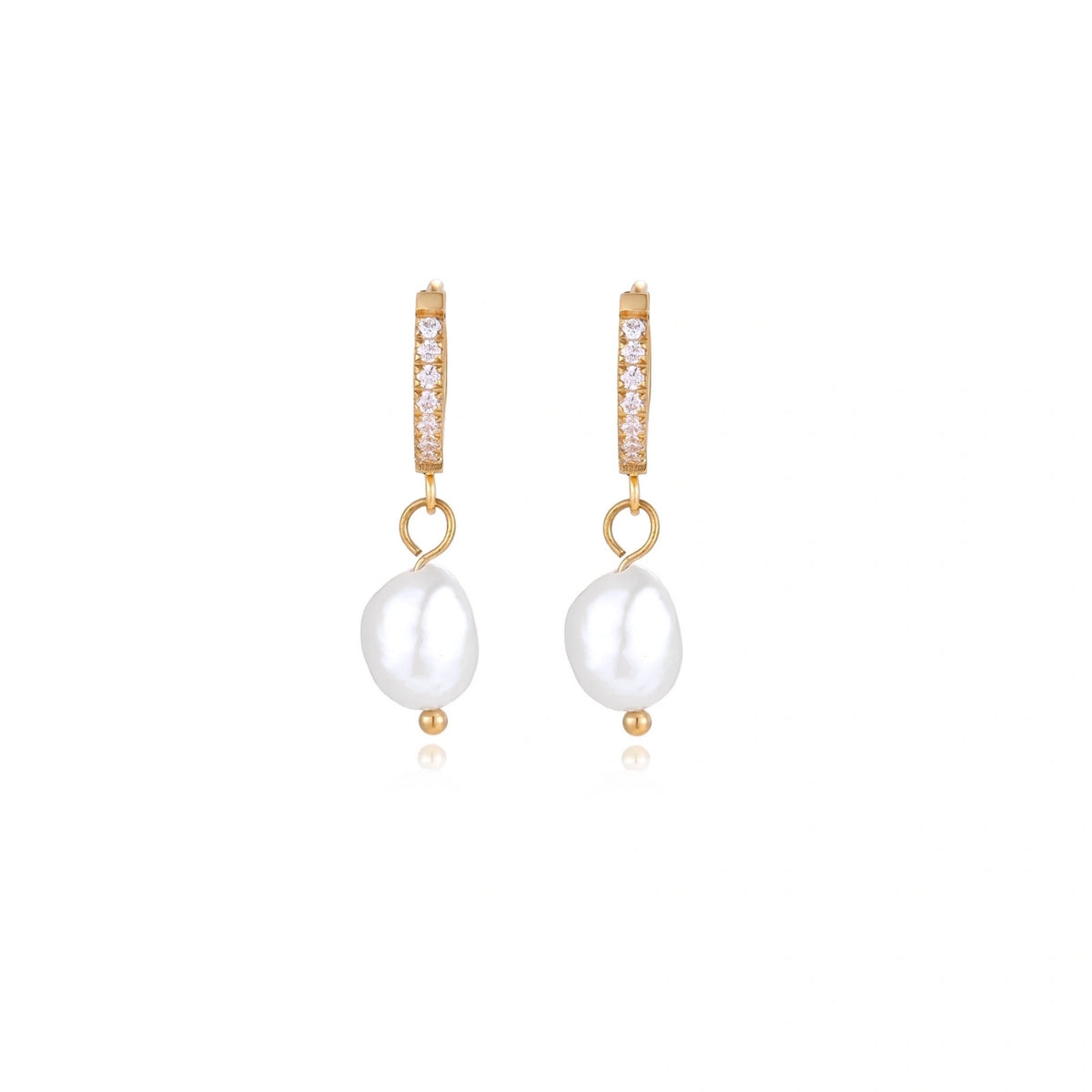 Gold huggie hoop earrings with pavé crystals and white freshwater pearl drops on cream background