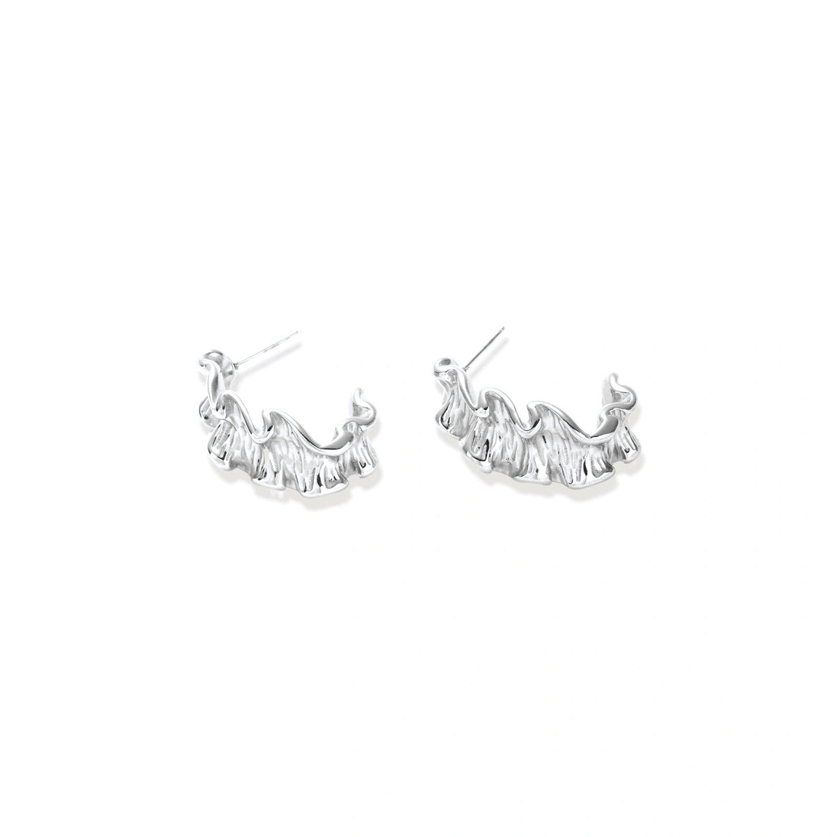 Textured white gold-plated hoop earrings with flowing wave pattern against cream background, showing dimensional rippled surface.
