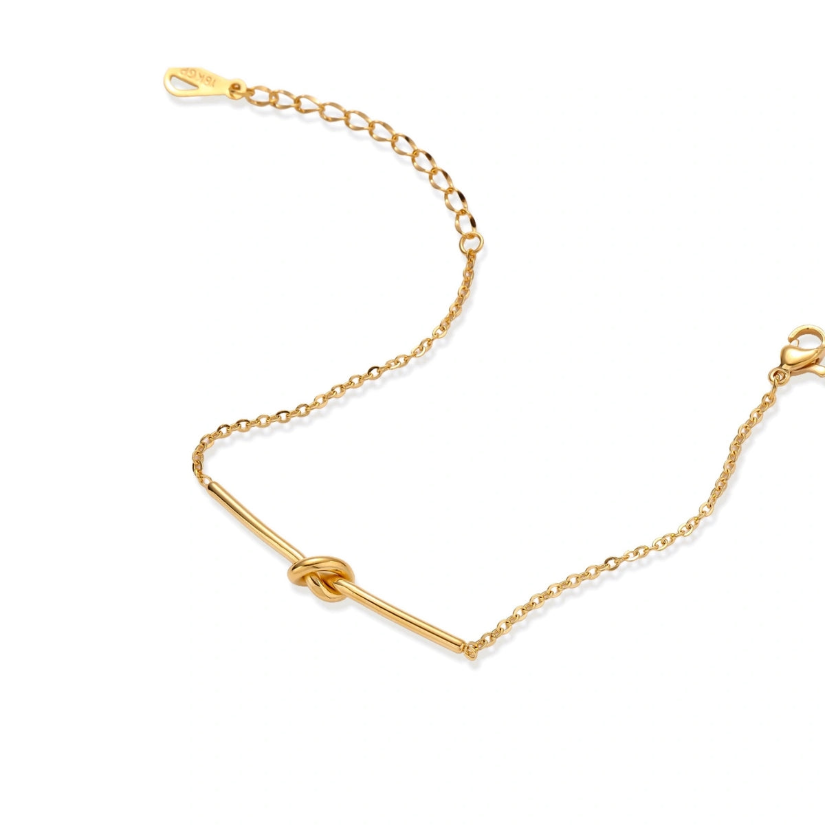 Delicate gold chain bracelet with minimalist bar and centered knot detail on cream background