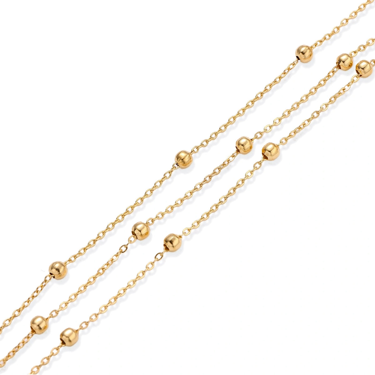 Three-strand gold-plated bracelet with clustered ball beads and adjustable clasp on cream background