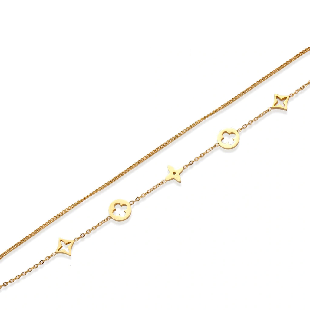 Double-layer gold-plated bracelet with quatrefoil and star charms on cream background, 18K gold finish.