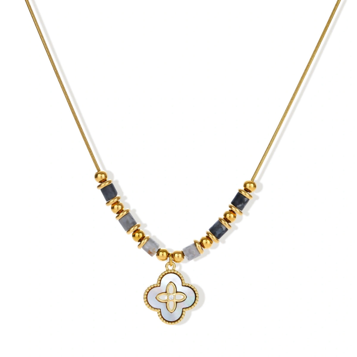 Gold-toned beaded necklace with grey stones and quatrefoil abalone shell pendant on cream background.
