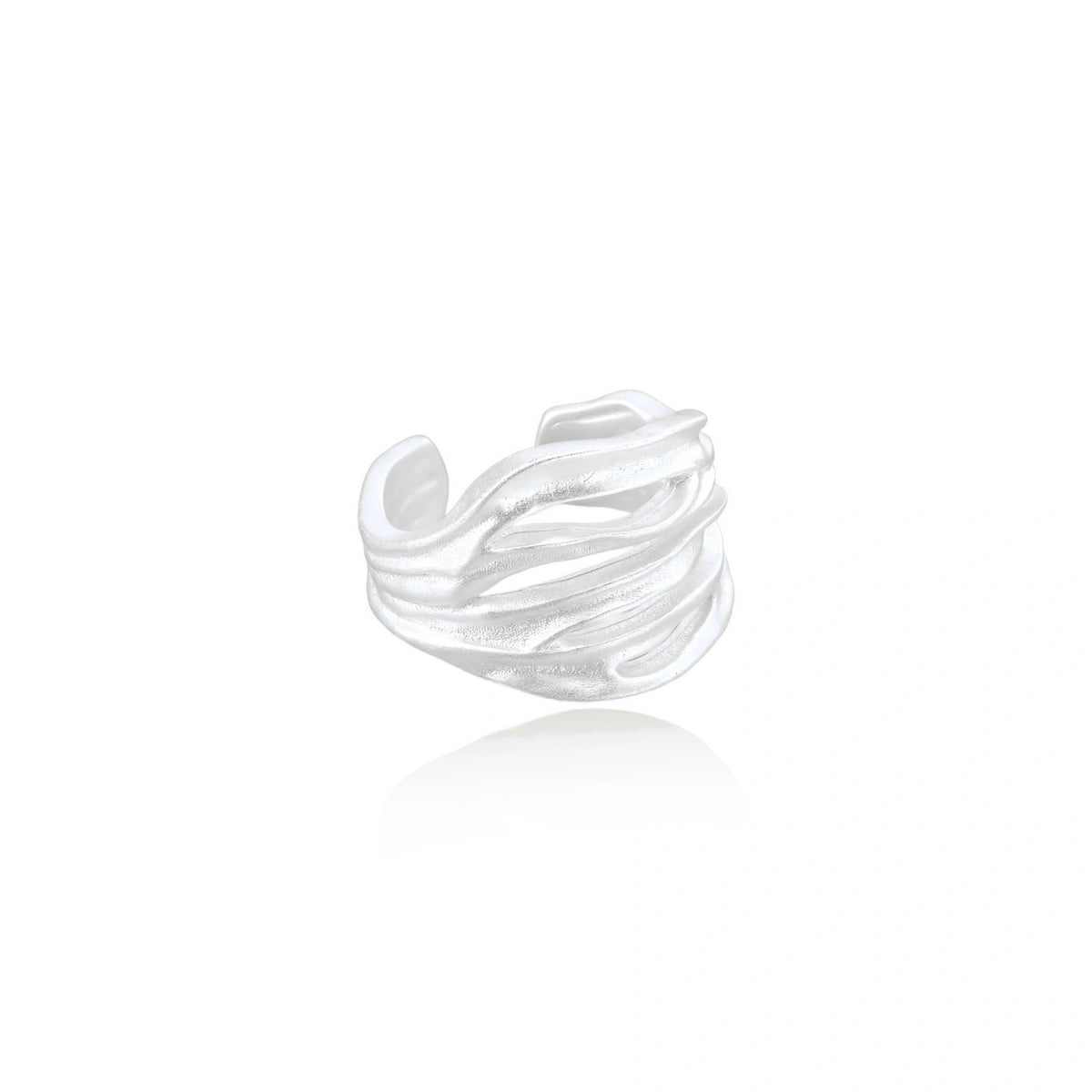 Wide sterling silver cuff ring with flowing wave patterns creating dimensional texture against cream background
