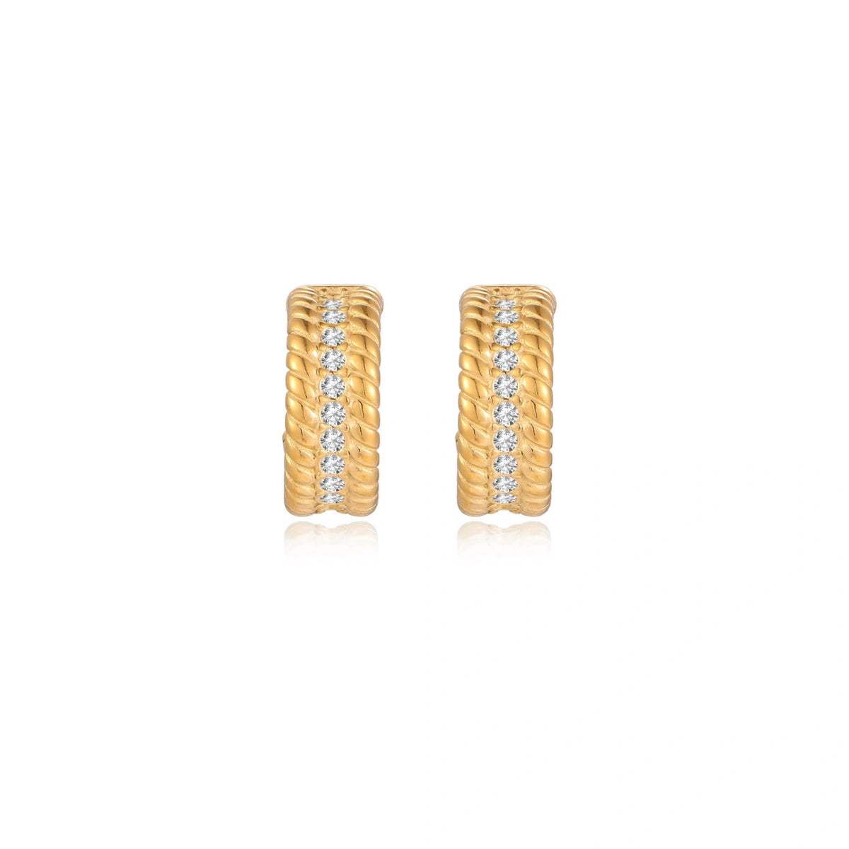 Textured gold huggie hoop earrings with raised ribbed rows creating dimensional sculptural design on cream background