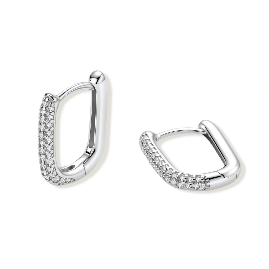 Close-up of platinum-plated sterling silver huggie hoops with pavé crystal setting on white background.